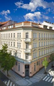 een groot wit gebouw met bomen ervoor bij Mamaison Residence Belgická Prague in Praag