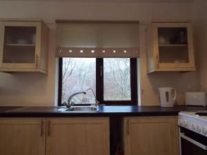 a kitchen with a sink and a window at The Singing Heart, TirNaNog Cozy Cottage near Lochgilphead !!HIDDEN GEM!! in Lochgilphead