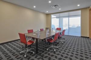 a conference room with a long table and red chairs at TownePlace Suites by Marriott Edmonton Sherwood Park in Sherwood Park