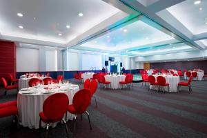 un salón de banquetes con mesas blancas y sillas rojas en Four Points by Sheraton Mexico City Colonia Roma, en Ciudad de México