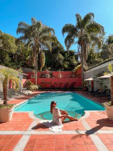 uma mulher sentada em frente a uma piscina em Hotel Reggia Catarina em Petrópolis