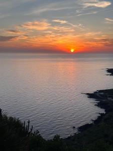 una puesta de sol sobre el agua con el sol en el cielo en La Casa Sul Tramonto en Pantelleria