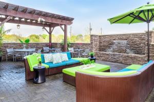 un patio con sofá, mesas y sombrilla en SpringHill Suites Houston NASA/Seabrook, en Seabrook