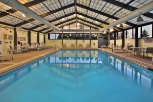 une grande piscine avec des chaises et des tables dans un bâtiment dans l'établissement SpringHill Suites by Marriott Chicago Southwest at Burr Ridge Hinsdale, à Burr Ridge