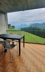 un tavolo nero e sedie su un balcone con vista di Superbe appartement 3.5 avec cheminée a Gruyères