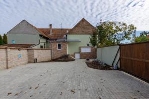 a large house with a fence and a driveway at Anova Apartman in Gyula
