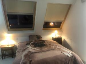 a bed in a room with two windows and two lamps at Guadarrama, ático nuevo con espectaculares vistas in Guadarrama