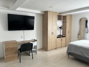 um quarto com uma secretária e uma televisão na parede em Hermoso loft en medellin em Medellín