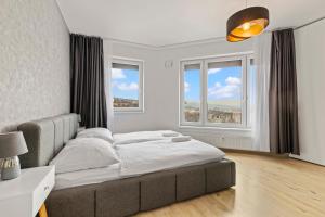 a bedroom with a large bed and two windows at LAM Premiere with best view in Bratislava in Bratislava