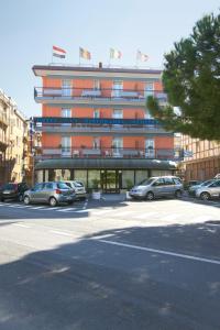 un gran edificio con coches estacionados en un estacionamiento en Hotel Mediterranée, en Spotorno