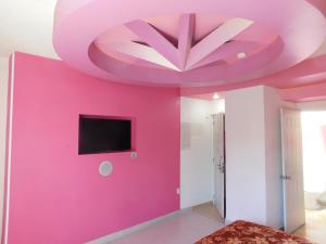 een kamer met een roze muur en een tv bij Hotel Extasis in Mexico-Stad