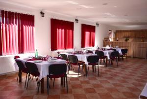 a dining room with tables and chairs and red windows at Casa Ildikó in Sovata