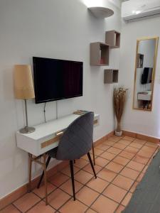 a desk with a television and a chair in a room at Régal de la Baie in La Trinité