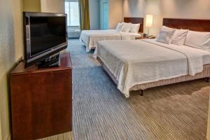 a hotel room with two beds and a flat screen tv at SpringHill Suites by Marriott Naples in Naples