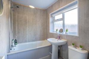 a bathroom with a sink and a bath tub and a sink at Spacious 3 Bed Flat-Free Parking in Gateshead