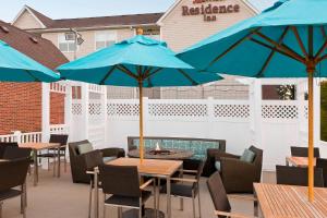 a patio with tables and chairs with blue umbrellas at Residence Inn Madison East in Madison