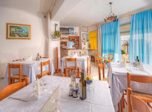 uma sala de jantar com mesas e cadeiras brancas e cortinas azuis em Hotel Villa Mena em Ischia