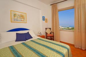 a bedroom with a bed and a large window at Hotel Villa Mena in Ischia