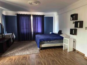 1 dormitorio con 1 cama con manta morada en Amplio departamento para 4 pers., en Cochabamba