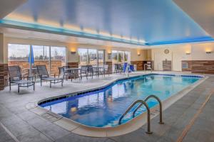 een zwembad in een hotel met stoelen en tafels bij Fairfield Inn & Suites by Marriott St. Louis Westport in Maryland Heights
