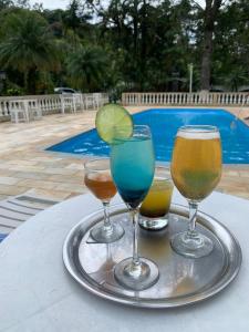 a tray with three different drinks on a table at Hotel Pousada Casa Grande in Joanópolis