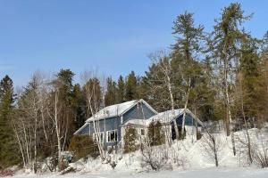 une maison dans les bois recouverte de neige dans l'établissement Le Chalet Bleu, aux pieds des Monts-Valin, à Saint-David-de-Falardeau