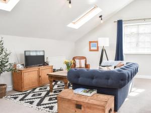 a living room with a blue couch and a tv at Elm House Studio in Christleton