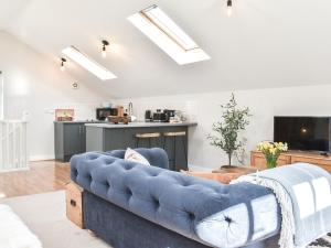 a living room with a blue couch and a kitchen at Elm House Studio in Christleton