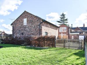 a brick house with a wooden fence in a yard at Elm House Studio in Christleton
