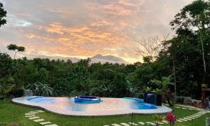 a large swimming pool in a yard with a sunset at BALAI BANAHAW Vacation Farm and Private Resort in Lucban