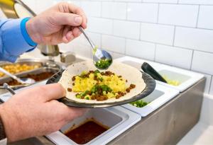 a person holding a plate of food with a spoon at Sonesta ES Suites Flagstaff in Flagstaff