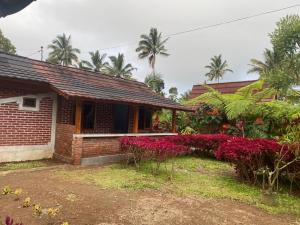 a brick house with red flowers in front of it at Wina Wani Bungalows Tetebatu in Tetebatu