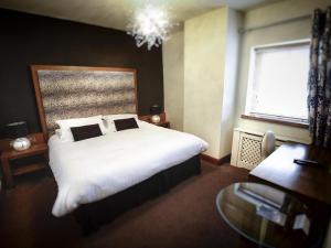a bedroom with a large white bed and a desk at Customs House Country Inn in Belcoo