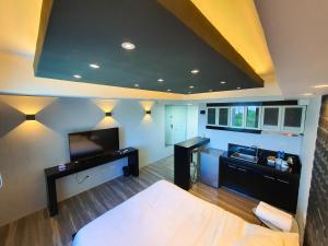 a room with a bed and a desk and a television at Burgundy McKinley Place Service Apartment in Manila