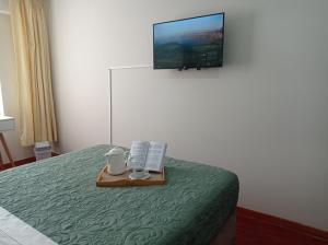 Habitación de hotel con cama y TV en la pared en Habi baño Compartido Grimaldo 1, en Lima
