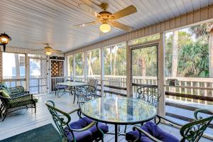 een afgeschermde veranda met tafels, stoelen en ramen bij Waller's Hollow in Edisto Beach