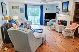 a living room with couches and chairs and a television at Driftwood Villa - 280 in Edisto Beach