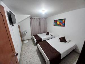 a hotel room with two beds and a tv at villa de las palmas in Palmira