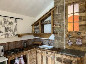 a kitchen with wooden cabinets and a stone wall at La tana club Suite Oro & Argento in Serina