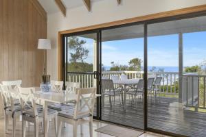 a dining room with a table and chairs on a balcony at Blue Oar Beach House Arrawarra Headland in Arrawarra