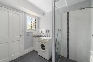 a white bathroom with a washing machine and a sink at Blue Oar Beach House Arrawarra Headland in Arrawarra