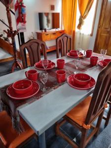 uma mesa com pratos vermelhos e copos de vinho em Cabaña Ceferino Ushuaia em Ushuaia