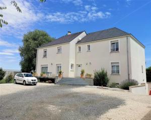 a white house with a car parked in front of it at Chambres d'hôtes GIDY in Gidy