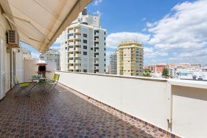 a balcony with chairs and a table on a building at By the Beach Duplex Apartment, Armacao de Pera, Algarve - Portugal in Armação de Pêra