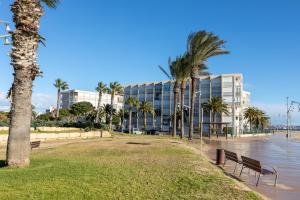 um parque com bancos e palmeiras em frente a um edifício em Just Oliver Holidays - Paradis Playa Seafront em La Pineda
