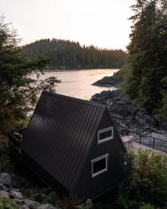 a black house next to a body of water at Duffin Cove Resort in Tofino