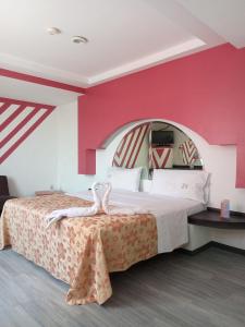 1 dormitorio con 1 cama grande y pared de color rosa en Hotel Afrodita en Ciudad de México