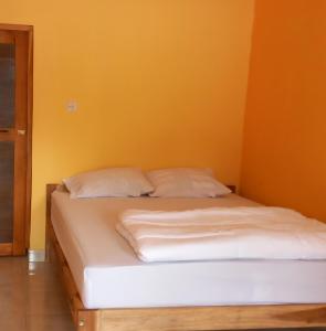 1 cama con sábanas blancas y almohadas en una habitación en Tange Guest House, en Ruteng