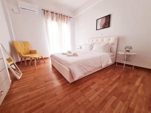 um quarto com uma cama branca e piso em madeira em Lovely 2-Bedroom 4th Floor House Large Patio em Atenas