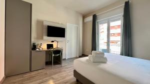 een slaapkamer met een bed, een bureau en een televisie bij ARKADIA 2.0 in Cagliari